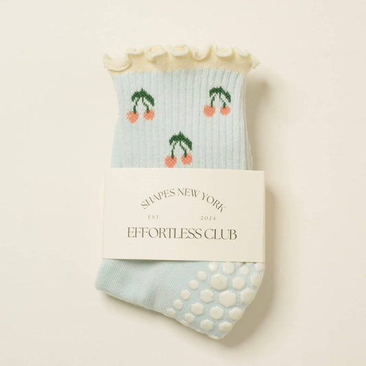 Pair of light blue socks with cherry design  on a beige background