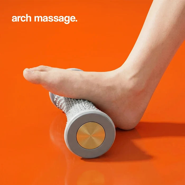 Arch massage roller with a textured surface, being used under a foot on an orange background.